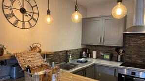 Una cocina moderna con encimera de madera, electrodomésticos de acero inoxidable y un reloj de pared grande.