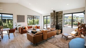 A spacious living room with a large sofa, a coffee table, and a fireplace. - Minaret Ridge | Holiday home close to the lake (Wanaka)