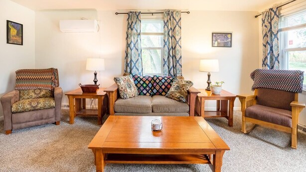 Un salon chaleureux avec un canapé, deux fauteuils, une table basse et deux petites tables d’appoint avec des lampes.