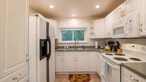 Une cuisine moderne avec des meubles blancs, un four à micro-ondes encastré, une cuisinière et un évier.