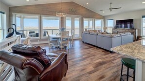 Uma sala de estar ampla com uma grande janela, uma mesa de jantar e um sofá.