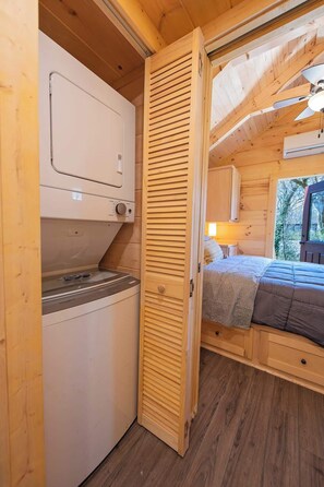 Uma cabana de madeira compacta com cozinha compacta, uma cama e uma janela com vista para o exterior.