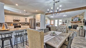 A spacious kitchen with modern appliances, a dining area with a wooden table and chairs, and a cozy living room with a fireplace.
