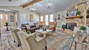 A spacious living room with a stone fireplace, a brown leather sofa, a beige armchair, and a coffee table.