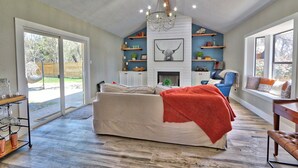 A spacious living room with a large sofa, a fireplace, and a bookshelf.