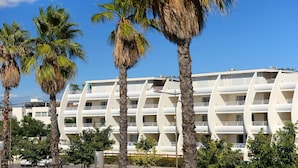 Ein modernes Hotel mit einzigartiger, geschwungener Architektur, mehreren Balkonen und einer Umgebung voller Palmen.