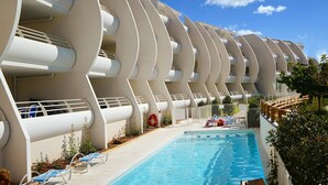 Ein modernes Hotel mit markanter, geschwungener Architektur, einem Schwimmbad und Liegestühlen.