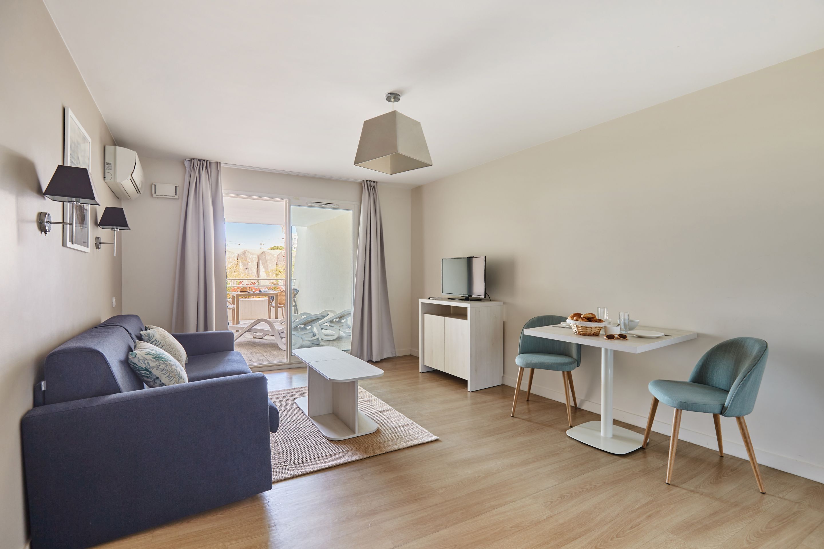 A modern living room with a sofa, a dining table, and a TV.