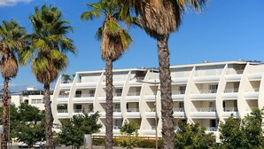 A modern hotel with a unique curved architecture, multiple balconies, and surrounded by palm trees.