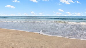 Een strand met heldere lucht en rustige golven.