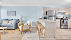 Een moderne keuken met een centraal eiland, roestvrijstalen apparatuur en lichtblauwe wanden.