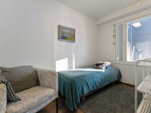 A small room with a bed, a sofa, and a window.