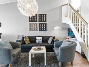 A modern living room with a grey sofa, two armchairs, a coffee table, and a chandelier.