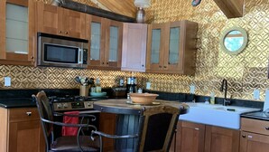 Una cocina con armarios de madera, microondas, estufa y un tapete rojo.