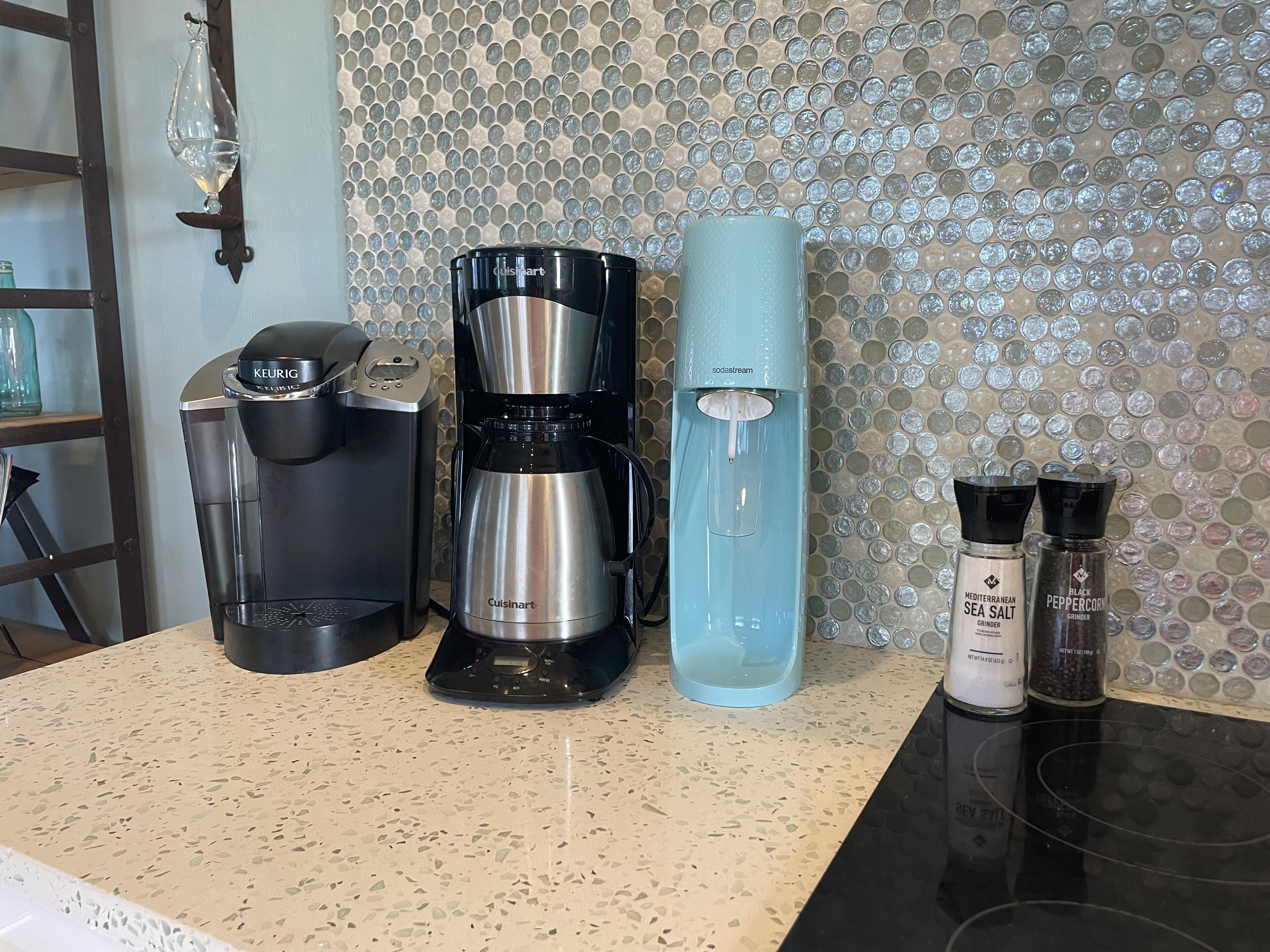 Een kitchenette met een koffiezetapparaat, een waterdispenser en twee kruidenpotjes.