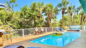 A wooden deck with a pool, lounge chairs, and a floating ring. - Private & Spacious [2300sqft] home w/Pool,Hot Tub,Golf Cart, Pet Friendly & Club (Captiva)