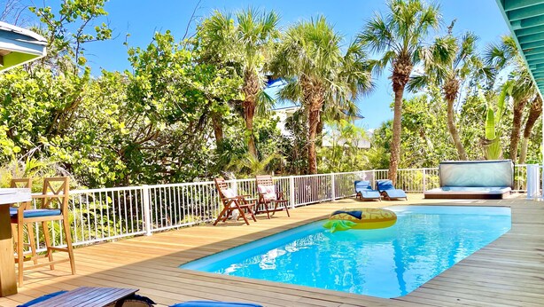A wooden deck with a pool, lounge chairs, and a floating ring. - Private & Spacious [2300sqft] home w/Pool,Hot Tub,Golf Cart, Pet Friendly & Club (Captiva)