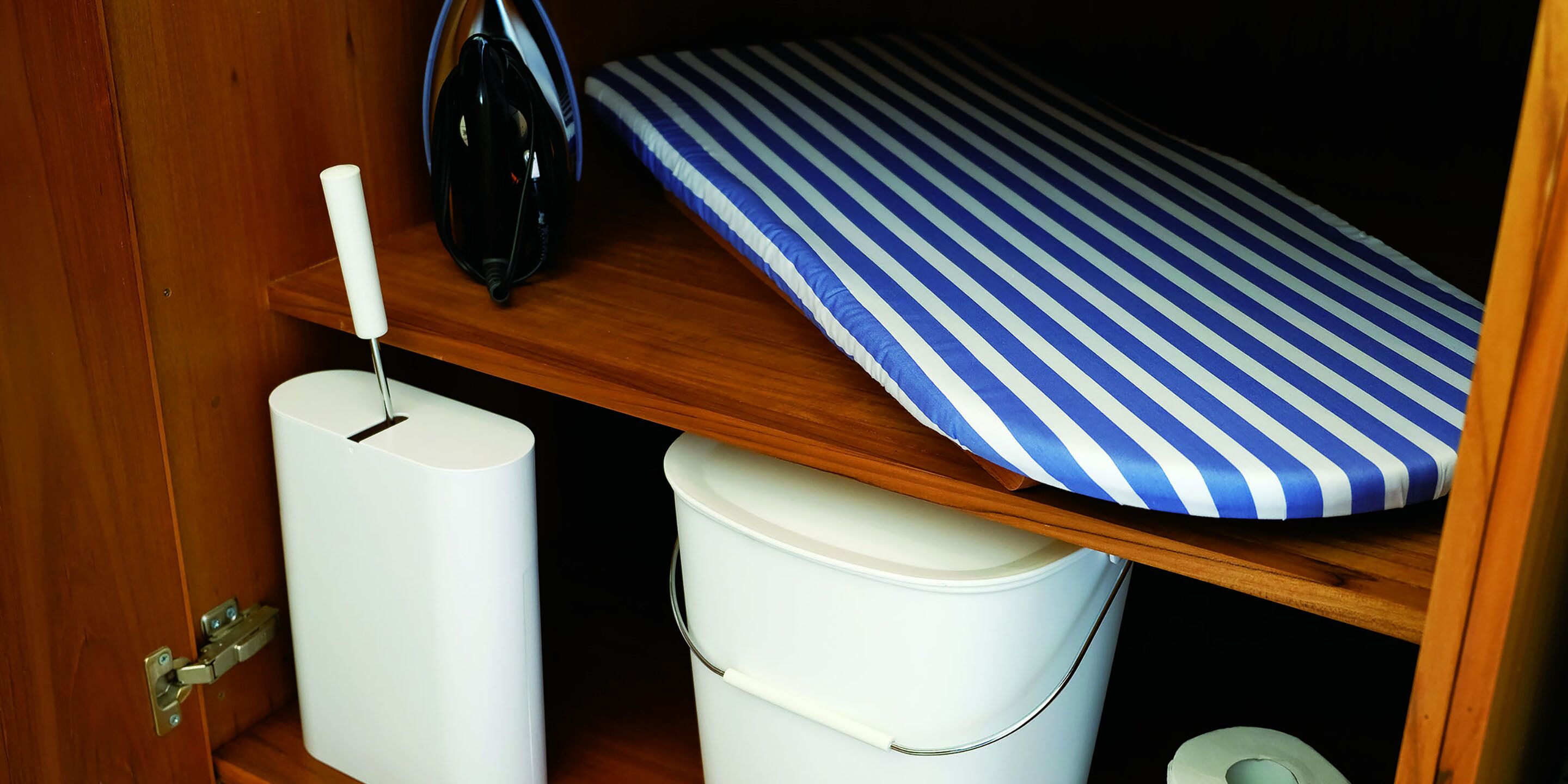 Een houten plank met een blauw-wit geruit kleedje, een witte emmer en een witte, cilindervormige vorm.