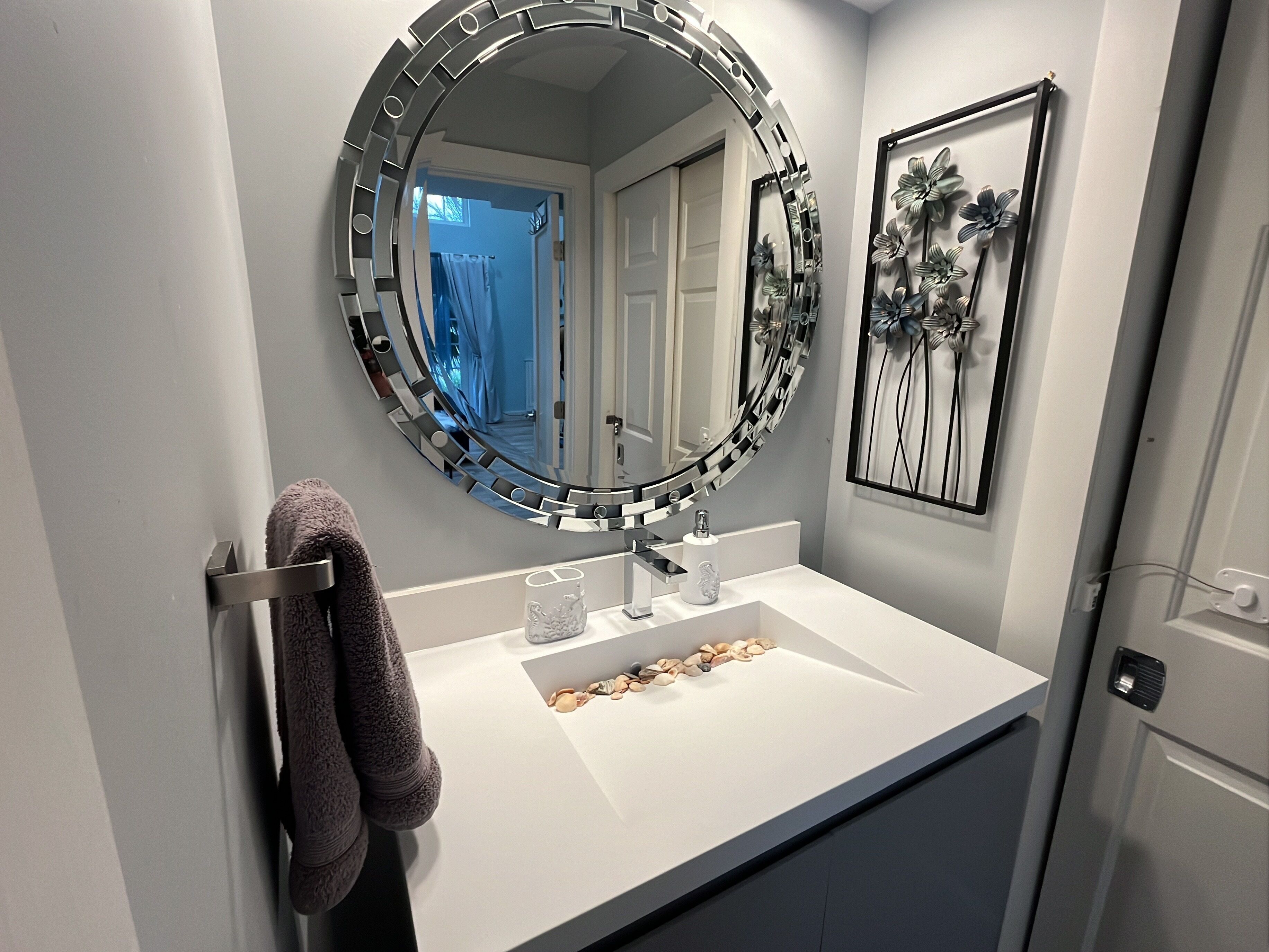 A bathroom with a round mirror, a white sink, and a towel rack.
