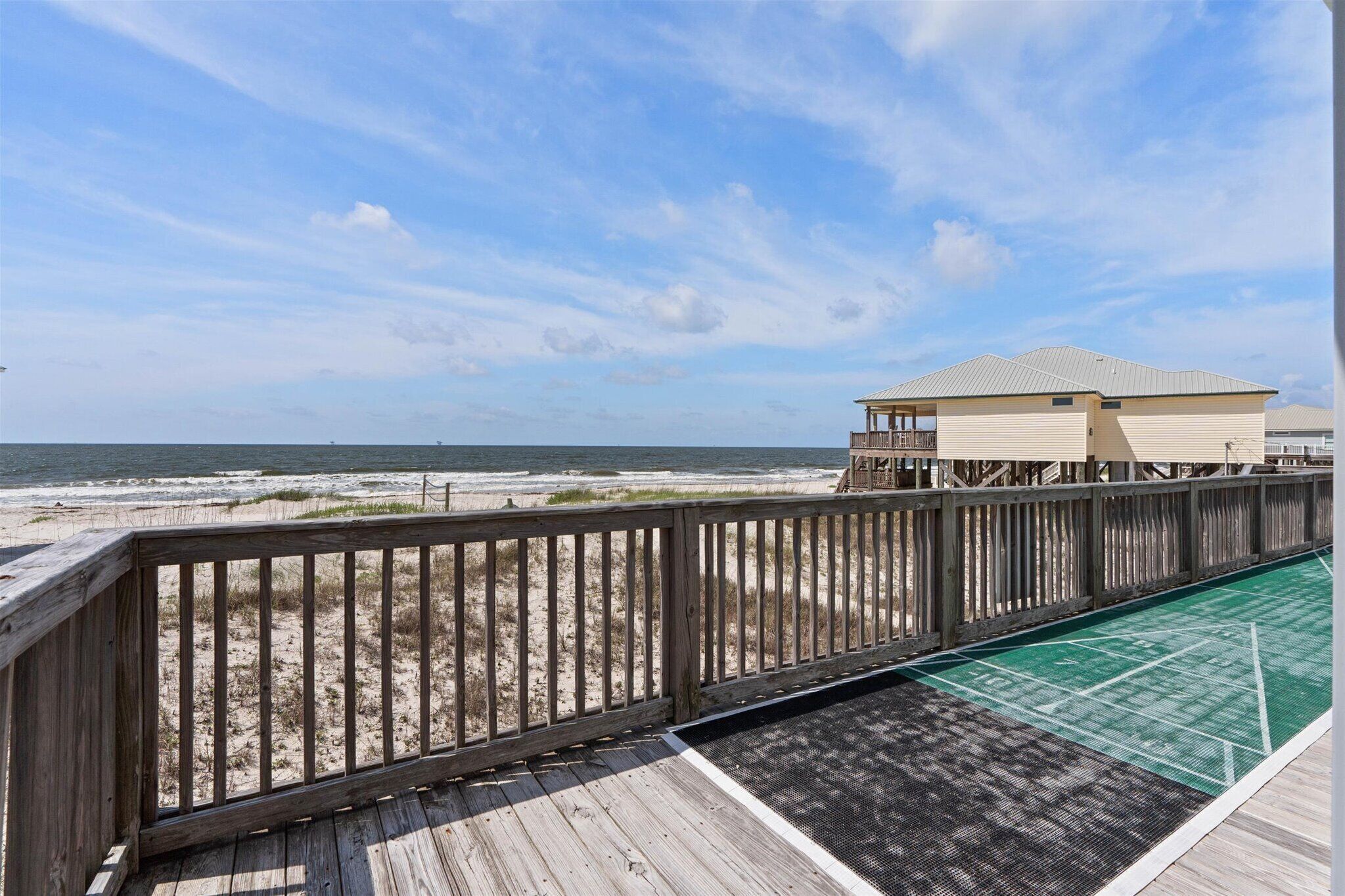 A wooden deck with a view of the beach and ocean.