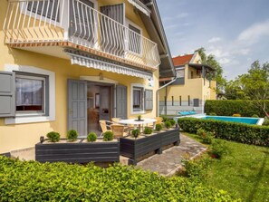 A two-story house with a balcony, a swimming pool, and a garden.