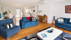 Una sala de estar moderna con dos sofás azules, una mesa de centro blanca y un mueble de madera.