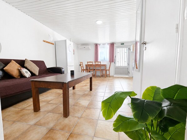 A room with a sofa, a wooden table, and a dining area with chairs.