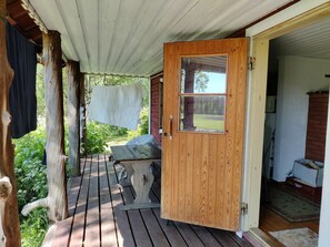 A wooden door leading to a covered porch with a bench and a hanging laundry line. - Kesämäki by Interhome (Punkaharju)