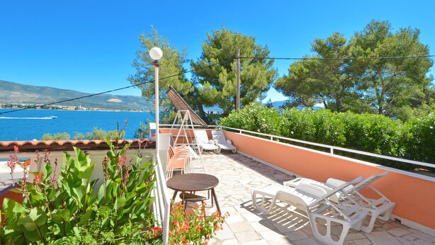 A terrace with a table and chairs, overlooking a body of water and a mountainous landscape. - B apartment with terrace with the sea view (Arbanija)