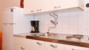 A kitchen with white cabinets, a stainless steel sink, a coffee maker, and a stove. - B apartment with terrace with the sea view (Arbanija)