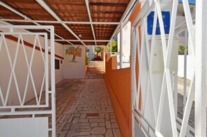 A covered walkway with a stone floor, white metal gates, and a sign reading "Vila Palma." - B apartment with terrace with the sea view (Arbanija)