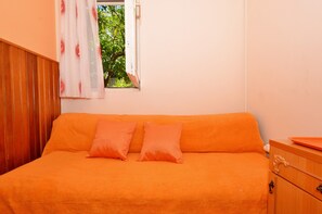 A room with a bed, a wooden dresser, and a window with a view of greenery. - B apartment with terrace with the sea view (Arbanija)