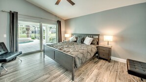 A bedroom with a bed, nightstands, a chair, and a ceiling fan.