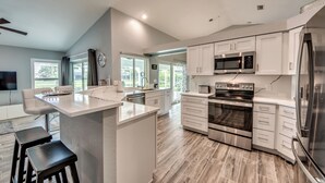 A modern kitchen with white cabinetry, stainless steel appliances, and a central island.
