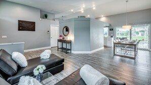 A modern living room with a sofa, a coffee table, and a dining area with a table and chairs.