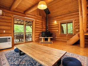 A log cabin interior with a wooden table, a fireplace, and a large window overlooking greenery. - Rental Villa No 818 LDK 18 tatami mats  Western / Yama-gun Fukushima (Yama-gun)