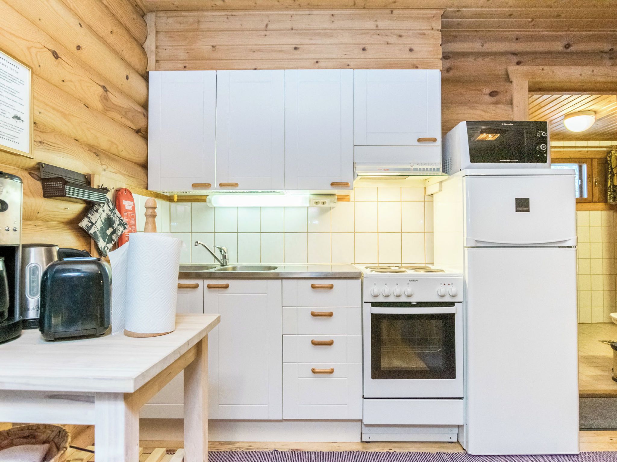 A kitchen with white cabinets, a stove, a microwave, and a refrigerator.