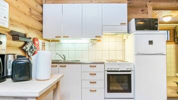 A kitchen with white cabinets, a stove, a microwave, and a refrigerator.