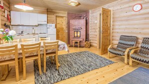 Acogedor interior de una cabaña de troncos con comedor, cocina y zona de estar.
