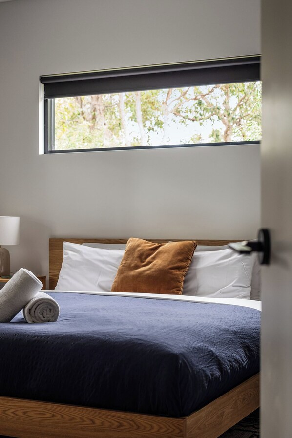 Un dormitorio con cama, ventana y mesita de noche.
