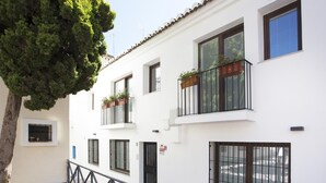 Un bâtiment blanc doté de nombreuses fenêtres et de balcons, dont certains sont ornés de plantes.