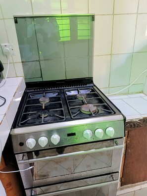 A stainless steel stove with four burners and a control panel with knobs.