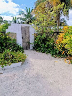 A pathway leading to a gated entrance surrounded by lush greenery and palm trees.