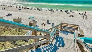 A beach with a wooden staircase leading down to the sand, a row of beach chairs, and umbrellas. - 248 Beach Bike Way (Inlet Beach)