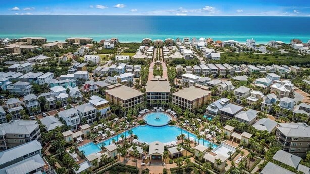 An aerial view of a resort with multiple buildings, a central pool, and a view of the ocean. - 248 Beach Bike Way (Inlet Beach)
