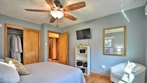 A bedroom with a bed, a ceiling fan, a TV, a wardrobe, and a chair.