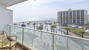 Un balcon avec vue sur la mer et un bâtiment moderne.