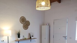 Un comedor con una mesa de madera, sillas, una lámpara colgante, una puerta blanca y un estante con objetos decorativos.