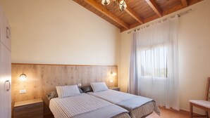 A double bed with striped bedding, wooden headboard, bedside lamps, and a window with curtains. - Holiday Apartment "Casa Quemahierro 2" with Teide View, Pool and Garden (Icod de los Vinos)