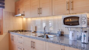 A modern kitchen with wooden cabinets, a stainless steel sink, a microwave, a kettle, and a toaster. - Holiday Apartment "Casa Quemahierro 2" with Teide View, Pool and Garden (Icod de los Vinos)